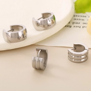 Detailed close-up of smooth silver hoop earrings and triple-row textured band designs