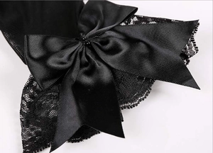 Macro shot of black satin bridal glove with elegant lace trim and beaded bow detail