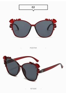 Macro detail of red floral crystal embellishments on oversized cat-eye sunglasses frames
