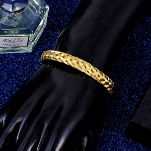 Detail of a wide gold woven mesh cuff bracelet in stainless steel on a black hand model