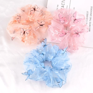 Detail of sheer mesh scrunchies with 3D butterfly charms in pink, orange and blue