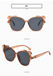 Macro view of C3 cat eye sunglasses with amber frames and faux crystal flower accents