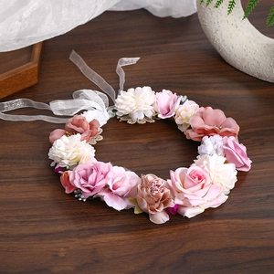 Macro shot of realistic pink cloth rose wreath with elegant white ribbons on dark wood