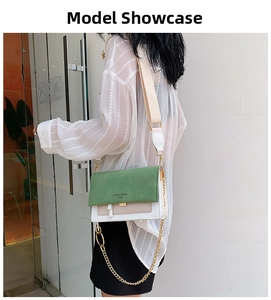 Detail of color-block crossbody bag with green suede flap and gold chain strap on model