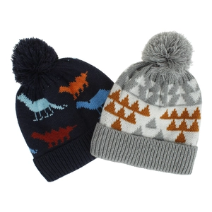 Detail shot of two knitted beanies with dinosaur and geometric patterns and pompoms