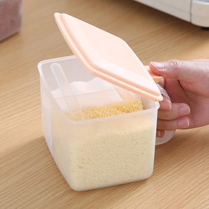 Pink circular seasoning box with clear spoon being opened on a wooden table