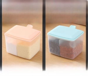 Close-up of dual-compartment plastic seasoning boxes in pink and blue with spoons