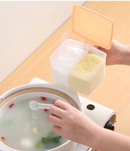 Action shot of hand using a spoon to add seasoning from the dual-compartment plastic jar