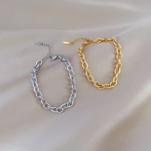 Minimalist titanium steel chain bracelets in gold and silver on beige silk fabric