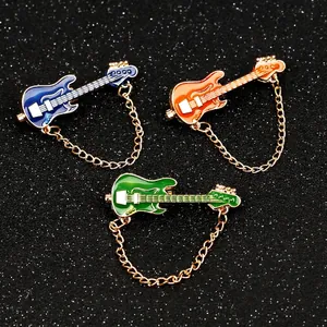 Set of three colorful guitar brooches with gold chains on a dark shimmering background