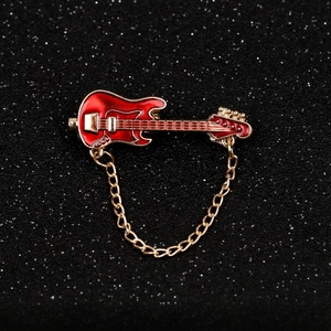 Detailed view of a red enamel guitar brooch with gold metal edges and decorative chain link