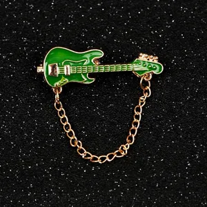 Golden electric guitar brooch with green enamel finish and delicate chain detail