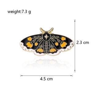 Detail view of enamel moth brooch with yellow floral patterns and size specifications