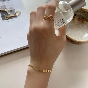 Detail of 18K gold plated infinity ring and round disk bracelet on hand