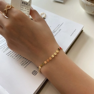 Minimalist gold round disc bracelet and infinity ring styled with a perfume bottle