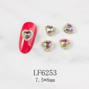 Detail of 3D heart nail charms with AB crystals and gold base on marble surface