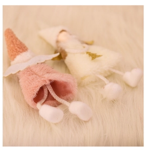 Detail of plush angel ornaments with pointed knit hats and wings on white faux fur