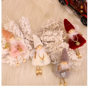 Detail of plush Christmas angel ornaments with knit hats and sequin wings on snowy background