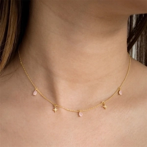 Close-up of gold choker featuring pink teardrop pendants and cutout star charms