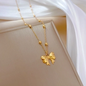 Titanium steel gold-plated bow necklace with delicate beaded chain on a jewelry display
