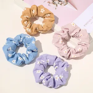 Set of four floral fabric hair scrunchies in yellow, pink, blue, and purple tones