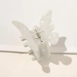 Close-up of pearl white butterfly hair claw with iridescent finish and silver metal spring