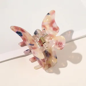 Detailed view of butterfly hair claw clip with pink and blue marbled acetate texture