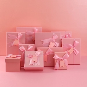 Various sizes of pink gift boxes with elegant ribbon bows and decorative tags
