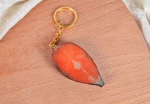 Porte-clés saumon réaliste avec texture détaillée sur fond de bois clair et tissu blanc