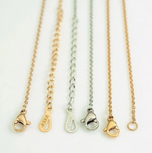 Macro view of 18KGP engraved metal tags on gold and silver stainless steel cross necklaces