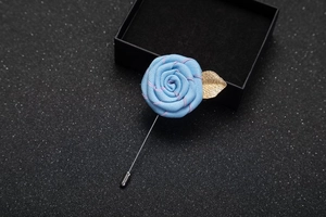 Detail of blue fabric rose boutonniere with pink stitching and gold metal leaf