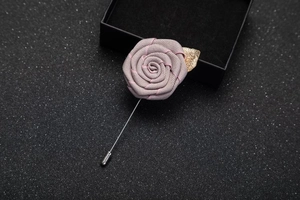 Detail of dusty pink fabric rose brooch with golden leaf and long silver needle pin