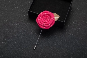 Close-up of pink fabric rose brooch with golden leaf on a black gift box background