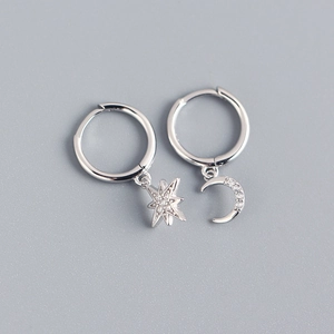 Macro view of asymmetric S925 sterling silver star and moon earrings with pavé zircons