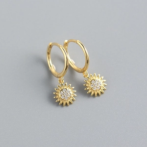 Macro detail of gold sunflower earrings with sparkling white diamonds and hoop closure