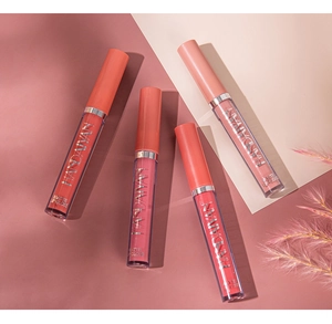 Set de cuatro brillos de labios mate presentados con flores secas en un fondo suave