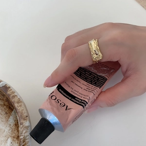 Detailed view of an irregular lava texture gold ring worn on the index finger