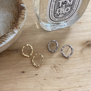 Irregular textured silver and gold stud earrings displayed on a rustic wooden background