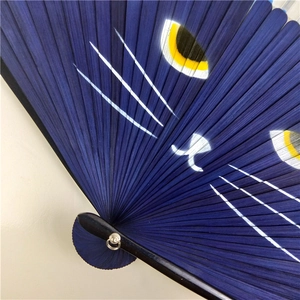 Close-up of a blue Japanese folding fan featuring a cute cat face on bamboo frame