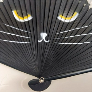 Close-up detail of a Japanese hand fan with yellow cat eyes and white whiskers design