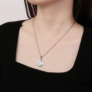 Close-up of vintage religious silver pendant necklace worn on a neck for detail