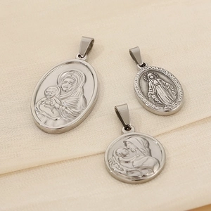 Detail of silver religious pendants featuring Virgin Mary engravings on beige fabric