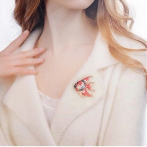 Close-up of tropical fish brooch with red and black enamel on white coat lapel