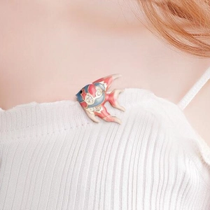 Detail of tropical angel fish brooch with red blue enamel and rhinestones on white knit