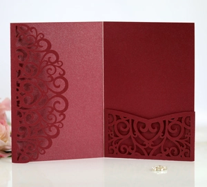 Detail of laser-cut burgundy invitation cover with elegant scrolling patterns on white