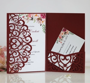 Detail of laser cut burgundy wedding invitation with white card and floral accents