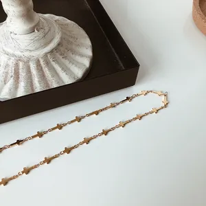 Close-up of gold-plated cross choker necklace featuring linked cross pendants on a table