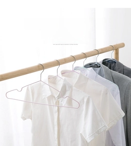 Detail of pink non-slip coat hanger with shoulder notches on wooden rail