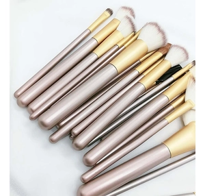 Detail of professional champagne gold makeup brush set with soft white and brown bristles