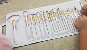 Detail of 24-piece makeup brush set with gradient bristles in a white roll-up pouch